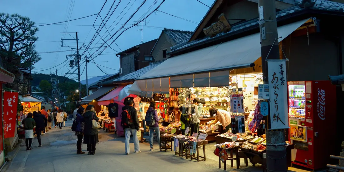 Une boutique de souvenirs ouverte sur une rue commerçante traditionnelle au Japon, à la tombée du jour